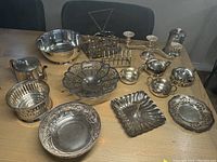 Wide view of the several silver plated serving pieces displayed on a wooden table