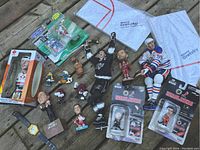 Overview photo showing all toys and figures including hockey bobbleheads, smurf figurines, Simpsons watch, and towels with Wayne Gretzky name.