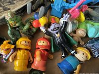 Close-up of colorful Fisher-Price Little People figures including yellow and red outfits, and a Jack-in-the-box clown figure with balloons.