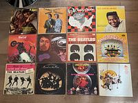 Overhead view of all 12 assorted vinyl albums laid out in a 4 by 3 grid showing cover art and artist names.