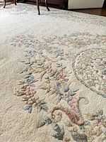 Close-up of the wool rug showing the detailed pastel floral pattern and the texture of the hand knotted pile.