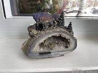 Front angled view showing the geode crystal interior with miniature mining figures and trees mounted on top, including 'ALASKA' label.