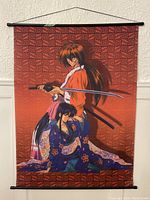 Wall scroll depicting Rurouni Kenshin with Kenshin holding a katana and Kaoru seated in floral kimono against a red patterned background.