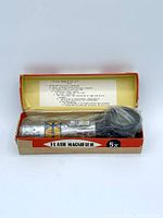 Photo showing the vintage 5X flash magnifier inside original branded box with usage instructions printed inside the lid.