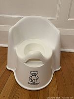 Front view of BABYBJÖRN white potty chair showing ergonomic design and teddy bear logo