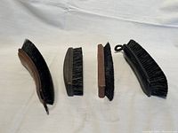 Four vintage shoe brushes laid side by side showing front profile and bristle side