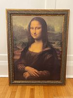 Full view of the framed Mona Lisa replica painting leaning against a wall on wooden floor.
