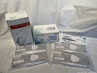 Photo showing multiple boxes and packages of N95 respirator masks including Dräger and MedSup Canada boxes plus several individually sealed CA-N95 masks laid out on white surface.