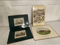 Four vintage English placemats or prints displayed upright and flat showing varied illustrations including Buckingham Palace and other British landmarks.