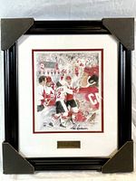 Framed print showing a scene from the 1972 Summit Series hockey game with Paul Henderson's signature at the bottom and a brass plaque below the mat.