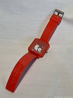 Front view of the watch showing red strap and square red watch face with Hello Kitty design and 'HELLO KITTY' text