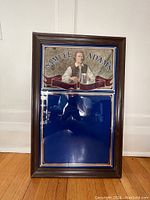 Front view of vintage wooden framed Samuel Adams beer sign mirror with depiction of Samuel Adams holding a beer stein and blue mirror panel below