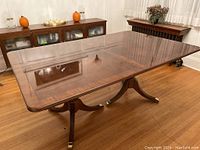 Full view of extended rectangular mahogany table with two pedestal bases and brass feet