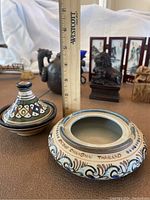 Photo of two ceramic containers, one with a 'Made Chiangmai Thailand' inscription and another with hand-painted patterns, ruler for scale about 4.5 inches tall.