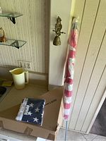 Image of folded American flag and unopened box for colonial walnut flag case on countertop.