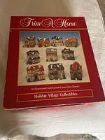 Box of Trim A Home Holiday Village Collectibles showing 10 illuminated hand-painted porcelain houses.