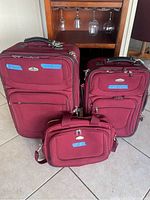 Front view of all three burgundy luggage pieces showing size difference and condition.