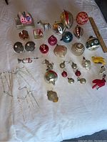All vintage ornaments arranged with ruler for scale showing variety of shapes, colors, and types including houses and animals.