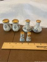 All three pairs of vintage porcelain salt and pepper shakers displayed with ruler for size reference.