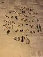 Full spread of earrings, charms, pins, and rings on fabric background