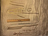 All items laid out on cloth with ruler for size reference. Includes necklaces and bracelets as described with mixed chain designs.