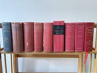 Photo showing nine Canadian Who's Who reference books on a wooden shelf against a white wall, with varying spine colors and titles.