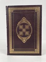 Front cover of the book showing dark brown leather with gold embossed decorative borders and central floral medallion.