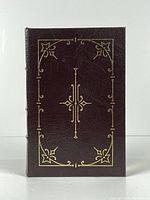 Front cover of the book showing dark brown leather with gold embossed decorative design.