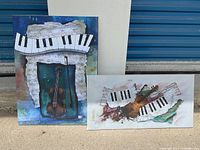 Both paintings placed outdoors against a white wall and blue garage door, showing full artworks and dimensions.