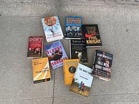 Photo of 9 used sports books arranged on the ground, showing covers with visible wear such as creases and folds