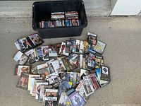 Wide angle photo showing multiple DVDs spread out in front of a large black plastic bin containing more DVDs.