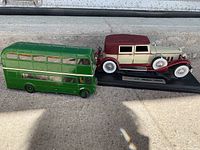 Top view showing side profile of the green double-decker bus alongside the maroon and cream classic car mounted on a black base.