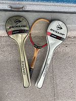 Photo of three tennis rackets including two Dunlop Turbo Plus Graphite rackets with covers and one wooden Slazenger racket.