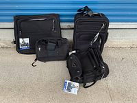 Four black Samsonite luggage pieces arranged on ground outside with tags attached, showing condition and set contents.