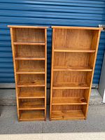 Two wooden shelving units standing side by side with multiple shelves and natural wood finish.