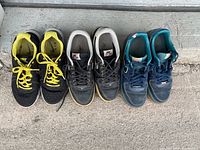 Three pairs of Nike Air sneakers arranged side by side on concrete, showing used condition.