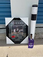 Photo of framed plaque with game tip-off photo and text about 2015-16 season, standing upright on ground with packaging corners attached.