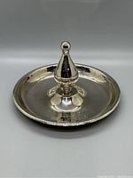 Front angled view of vintage metal bowling trophy ashtray showing reflective surface and central bowling pin figurine.