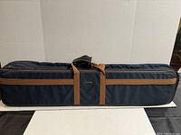 Front view of vintage Abercrombie & Fitch Golf N’ Go carrier bag, showing logo patch, brown leather handle, and navy blue fabric with brown trim.