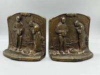 Front view of the pair of antique bronze bookends showing rural couple scenes in relief detail.