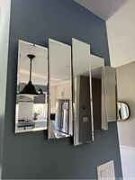 Front view of the 5 panel glass mirror mounted on a wall, showing reflected images of kitchen and living space.