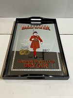 Front view of the vintage Beefeater branded advertising mirror serving tray, showing the black rectangular wooden frame with handle cutouts and the detailed mirror insert.