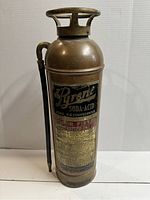 Front view of the copper fire extinguisher showing the Pyrene Soda-Acid label and discharge hose
