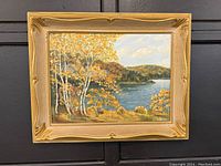 Framed oil on board painting showing autumn lake and landscape with birch trees and a serene sky.