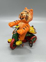 Front-side angle showing the orange tiger on green and red tricycle, highlighting the colorful details and condition.
