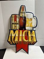 Front view of the Michelob beer metal advertising sign showing a can, bottle, and mug of beer with the word 'MICH' and a red arrow background.