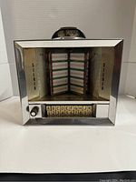Front view of vintage Seeburg jukebox showing song selection buttons, chrome framing, and coin slot marked 25 cents.