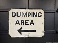Front view of the full metal sign with 'DUMPING AREA' text and left arrow.