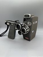 Side angle view of the Rondo Cinelec MD8T 8mm movie camera showing dual lenses, pistol grip with wrist strap, and flash unit.