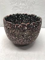Side view of reticulated pottery bowl showing textured surface and glaze coloration.